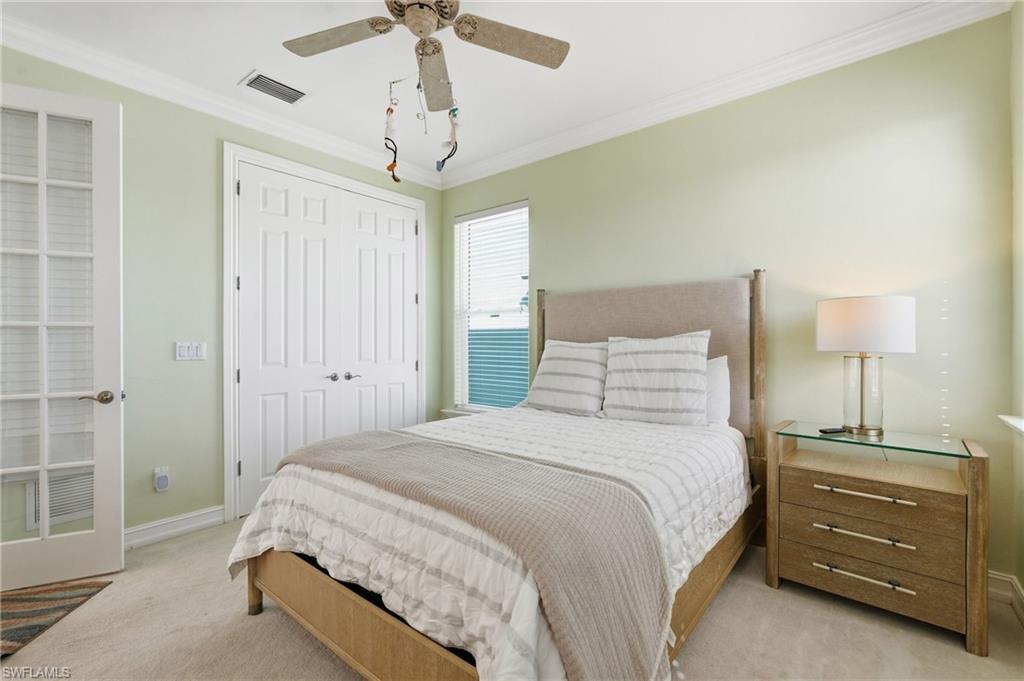 Recessed paneled closet doors, crown molding, French doors with glass panes, wood-finish flooring, and a ceiling fan - Virtually Edited Image