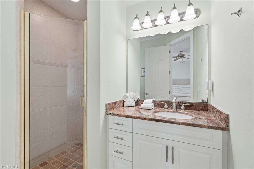 White vanity with a built-in sink, stone countertop, and brushed nickel fixtures - Virtually Edited Image