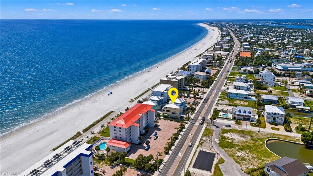 Expansive white sand beach, clear blue ocean, and coastal road - Virtually Edited Image