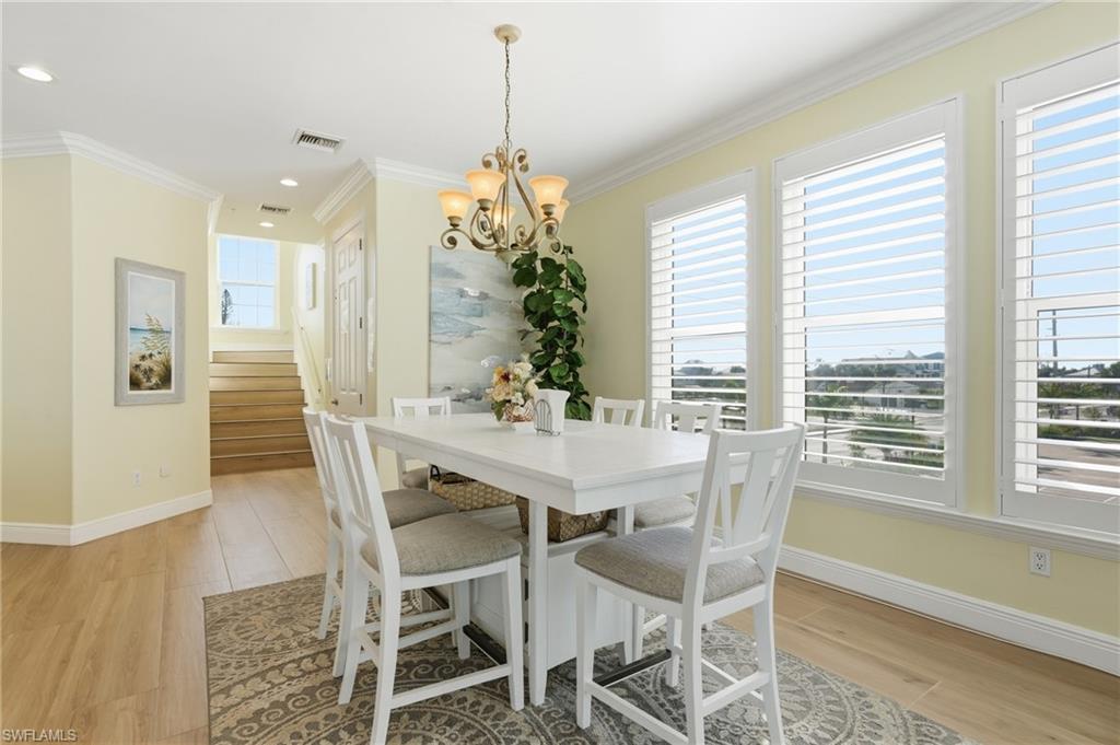 Wood-finish flooring, crown molding, and a decorative chandelier - Virtually Edited Image