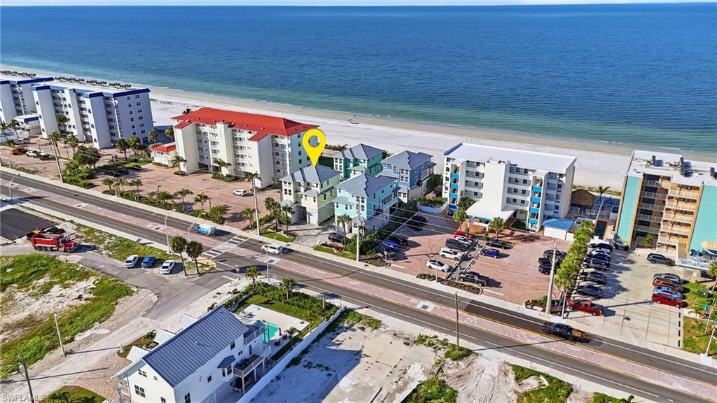 Waterfront property with direct beach access, multi-story structure with multiple balconies, and adjacent hardscape parking - Virtually Edited Image