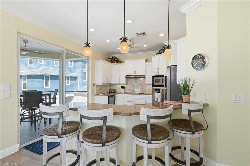 Kitchen featuring white cabinetry, granite countertops, stainless steel appliances, and recessed lighting - Virtually Edited Image