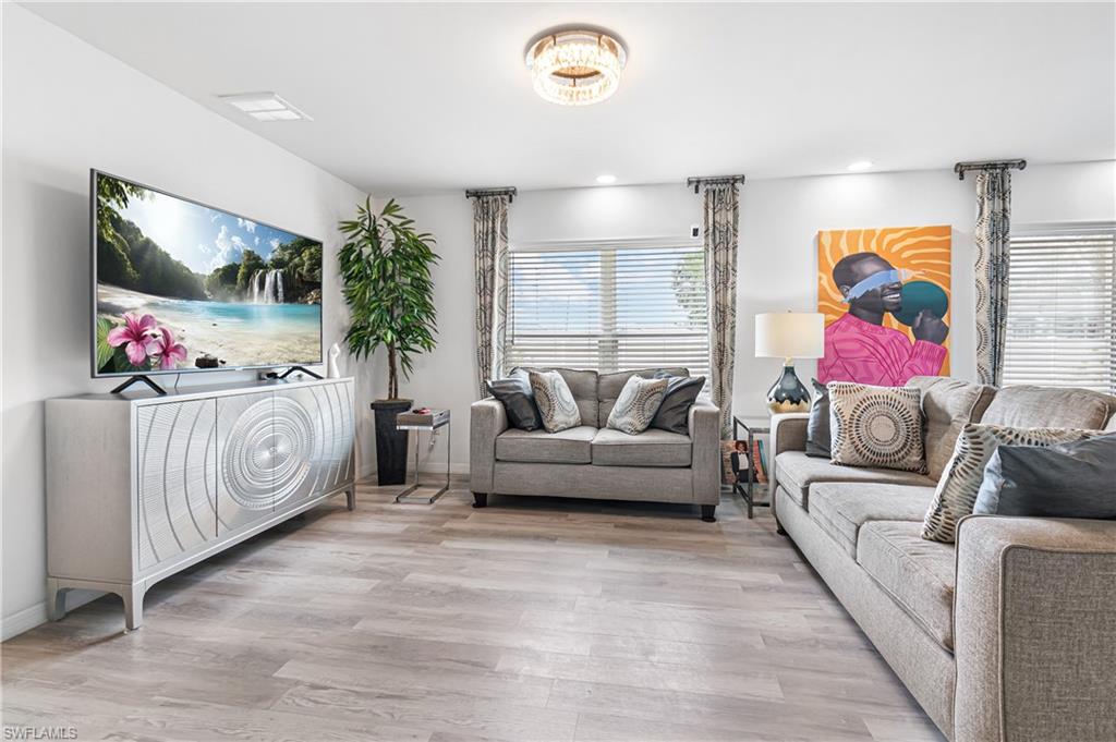 Open-concept living space featuring wood-finish flooring, recessed lighting, and a modern chandelier