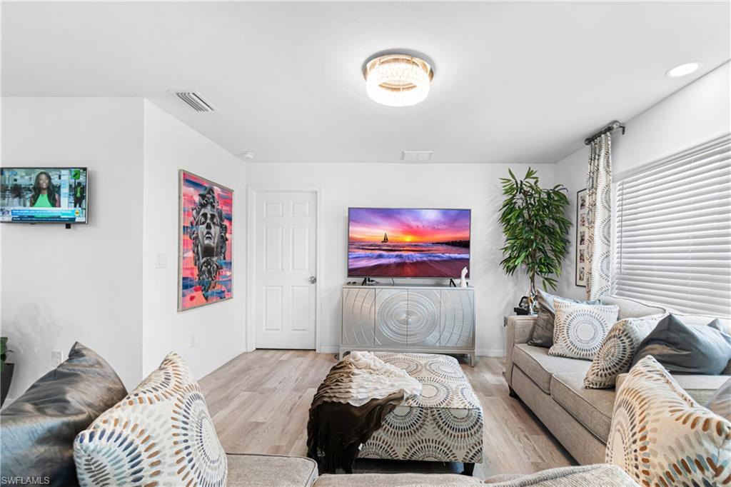 Bright living area featuring wood-finish flooring, white walls, recessed lighting, and a contemporary ceiling fixture