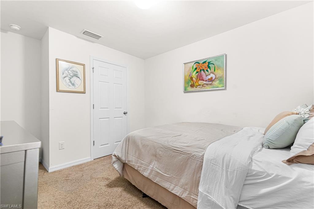 Carpeted room featuring white walls, a white paneled door, and a white ceiling with a flush-mount light fixture