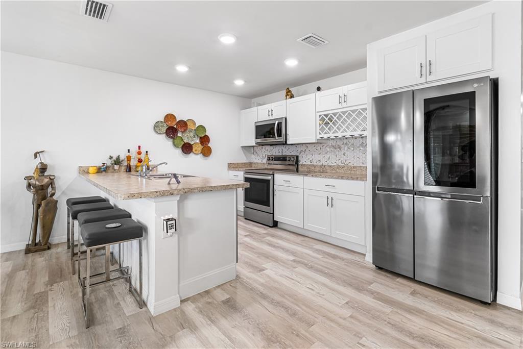 Modern kitchen featuring white cabinetry, light-toned wood-finish flooring, and recessed ceiling lighting