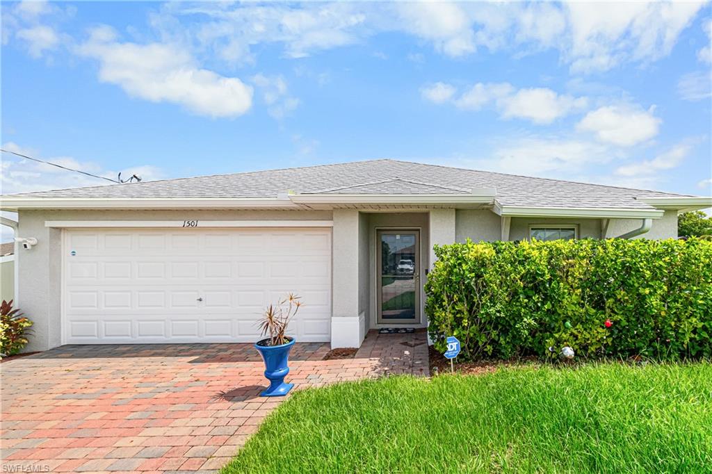 Exterior features a two-car garage with a white panel door, a glass-paneled entry door, and a paver driveway