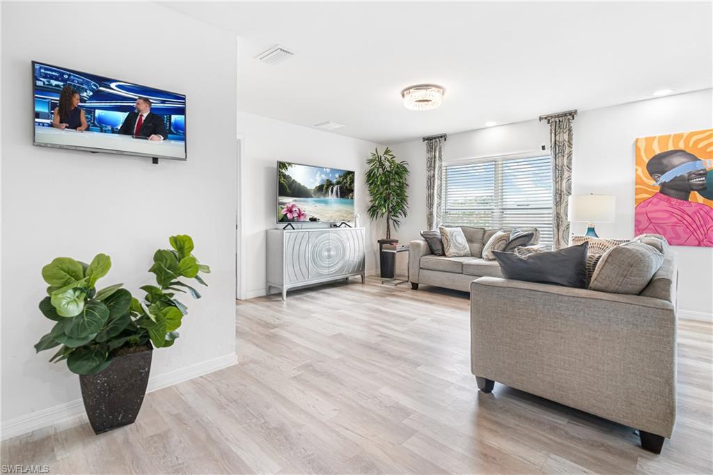 Open-concept living area featuring light wood-finish flooring, a contemporary ceiling light fixture, and recessed lighting