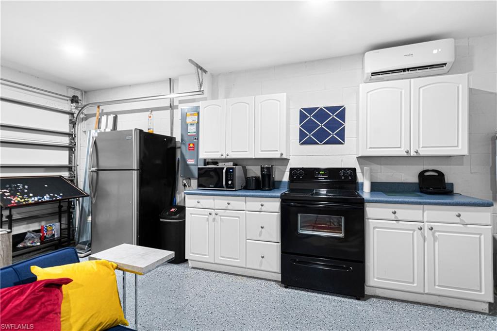 Garage space featuring a full kitchen setup with white cabinetry, blue countertops, and a black range