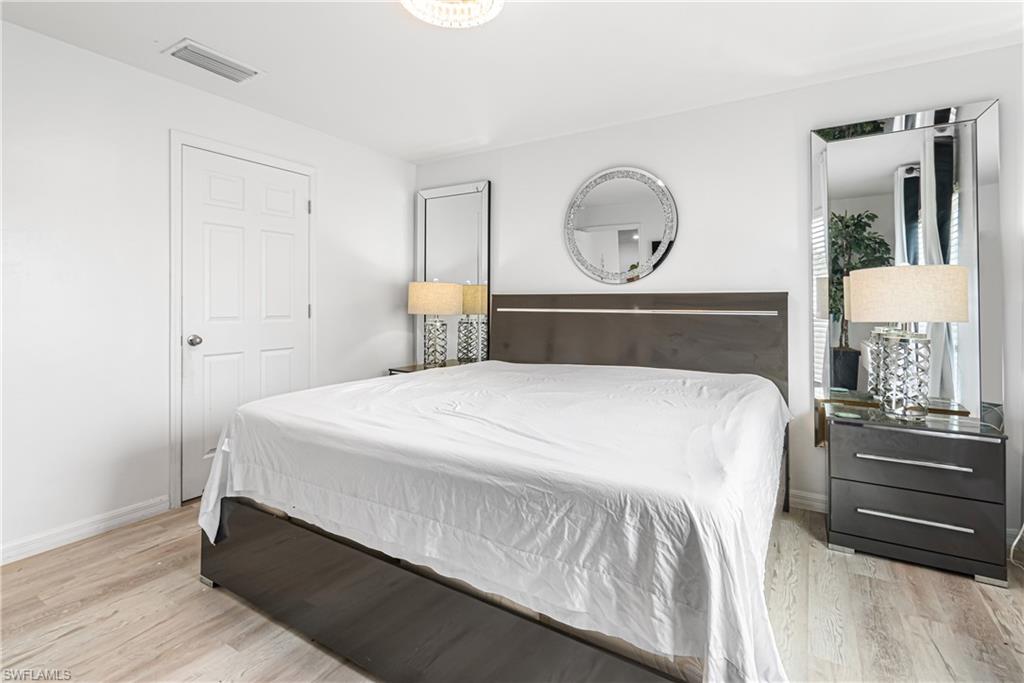 Bright interior space featuring light wood-finish flooring, a white paneled door, and a light fixture