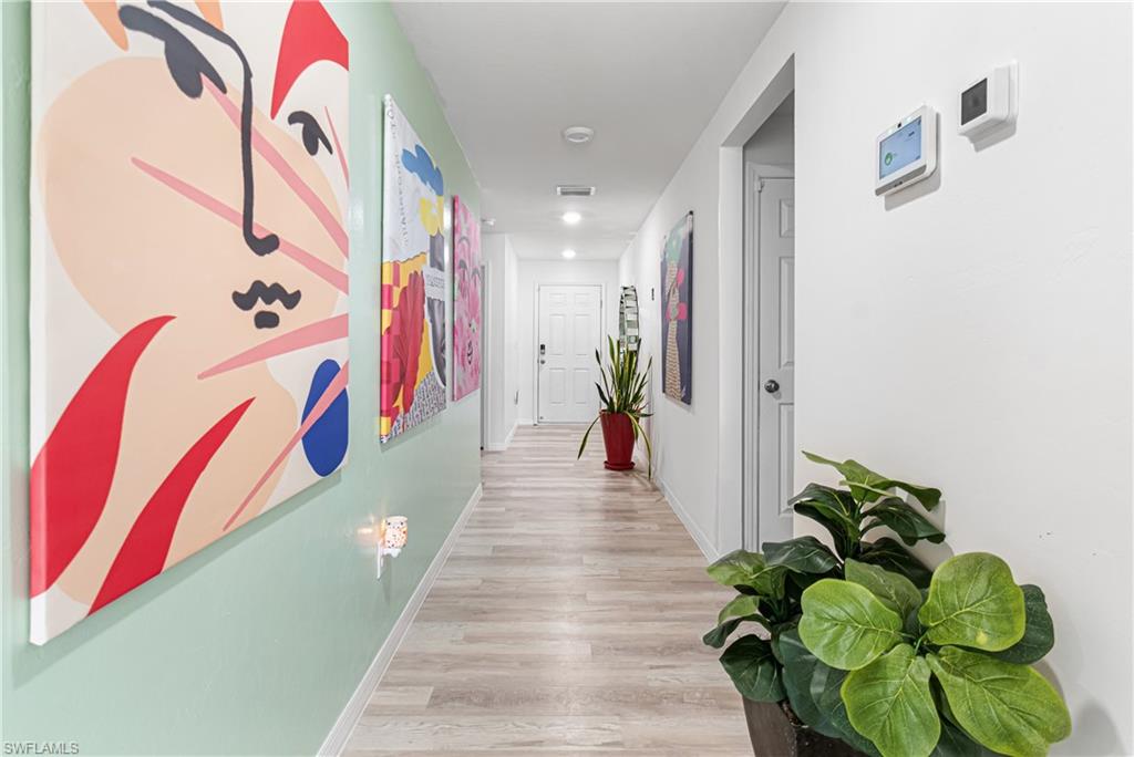 Hallway featuring wood-finish flooring, recessed lighting, and a wall-mounted control panel