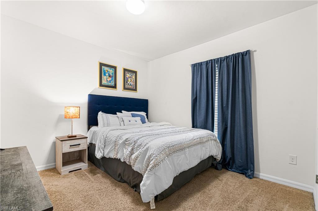 Carpeted bedroom featuring white walls, a single window with curtain rod, and an overhead light fixture