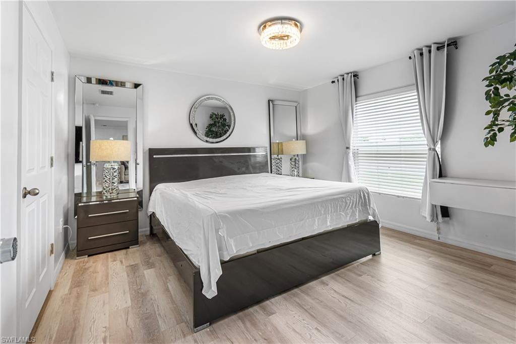 Bedroom featuring wood-finish flooring, a contemporary ceiling light fixture, and a window with horizontal blinds