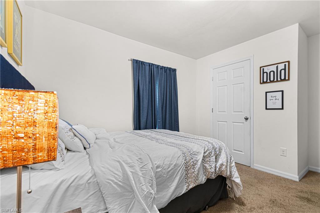 Interior room featuring neutral wall paint, white trim, and a textured carpet