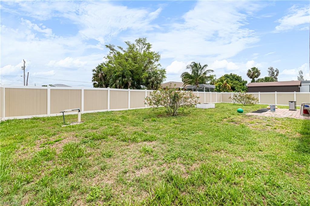 Expansive fenced backyard featuring a combination of tan and white privacy fencing