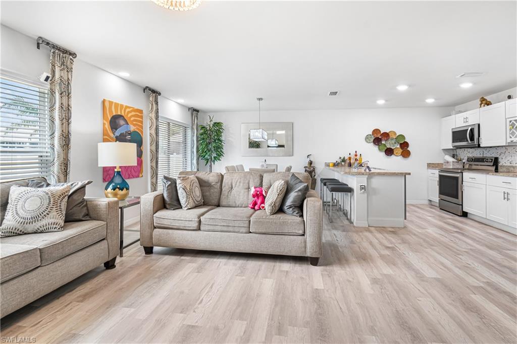 Open-concept living space featuring wood-finish flooring, recessed lighting, and large windows with blinds