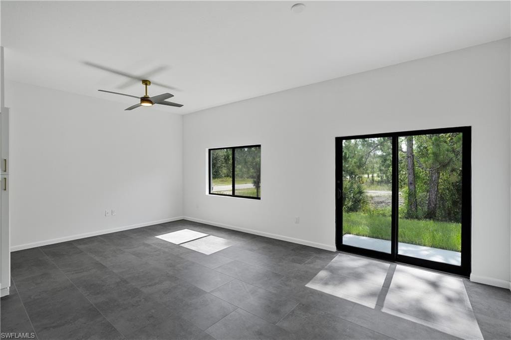 Spacious interior featuring a contemporary ceiling fan with integrated lighting, large format gray floor tiles, and a sliding glass door providing direct outdoor access