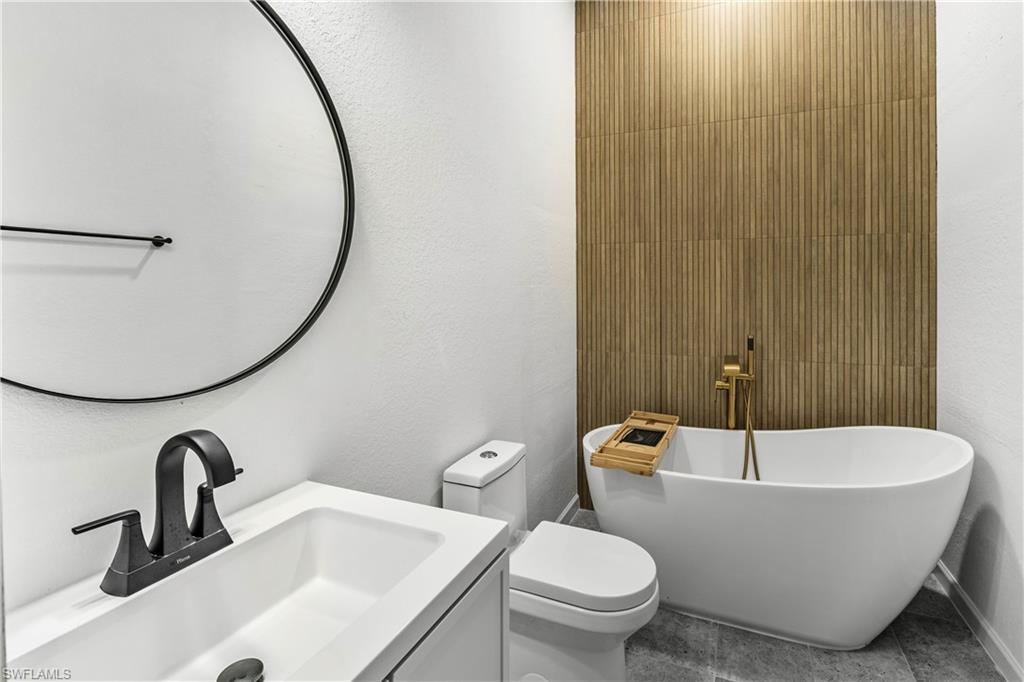 Modern bathroom featuring a freestanding soaking tub with a floor-mounted gold-finish faucet