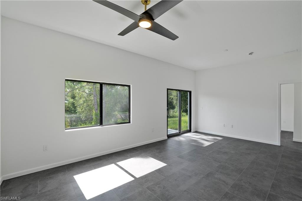 Spacious room featuring neutral walls, dark tile flooring, a modern ceiling fan, and recessed lighting