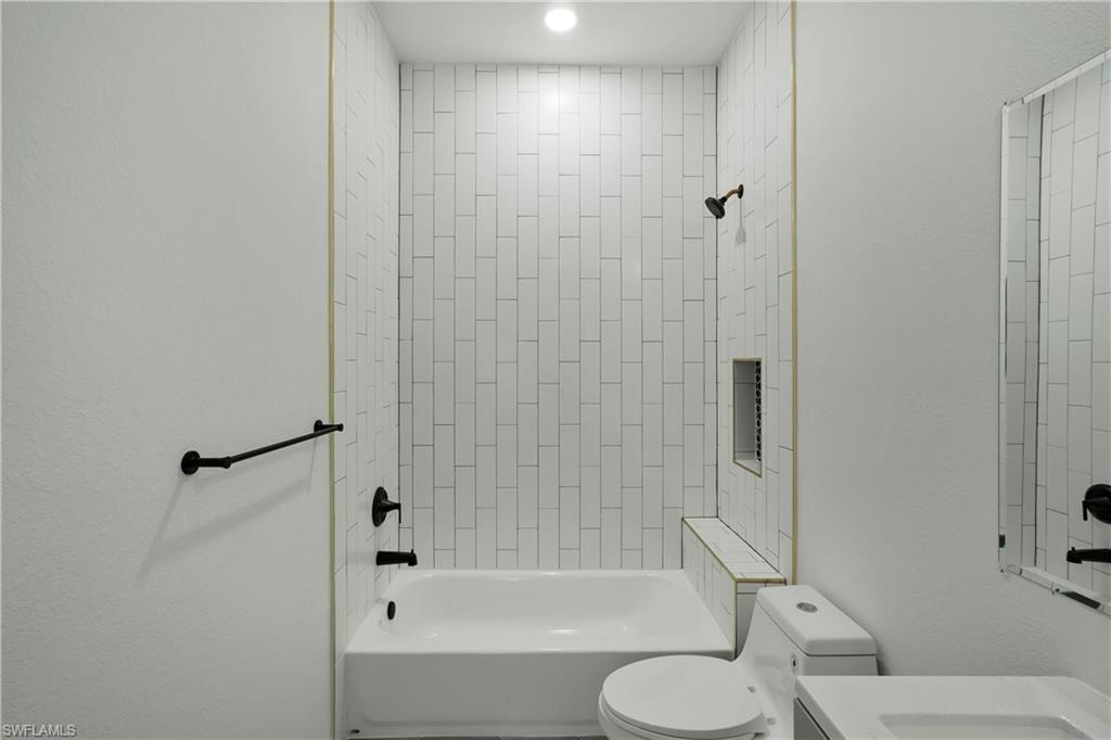 Bathroom featuring a white subway tile shower surround with gold accent trim, a built-in shower niche, and a shower bench