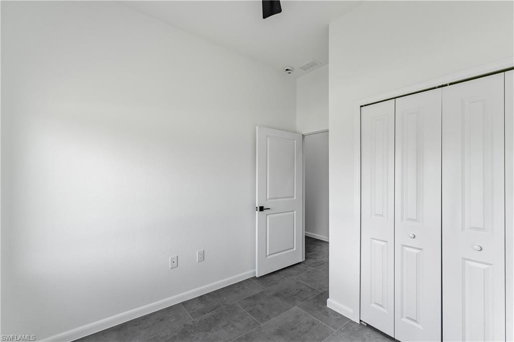 Interior room featuring neutral wall paint, grey tile flooring, and white bi-fold closet doors