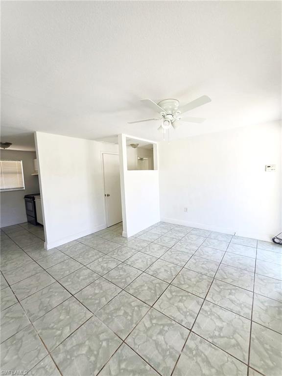 Spacious living area featuring light-toned tile flooring and a ceiling fan with integrated lighting