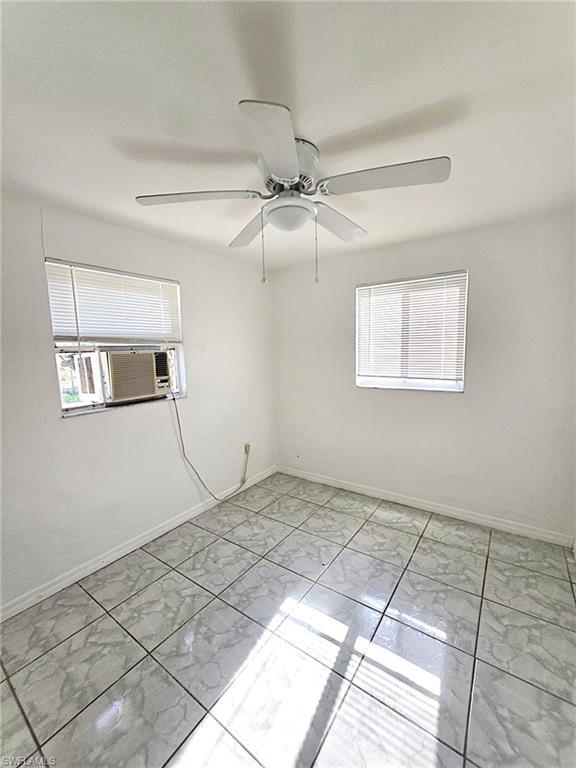 Room featuring light-toned tile flooring, white walls, and a ceiling fan with integrated lighting