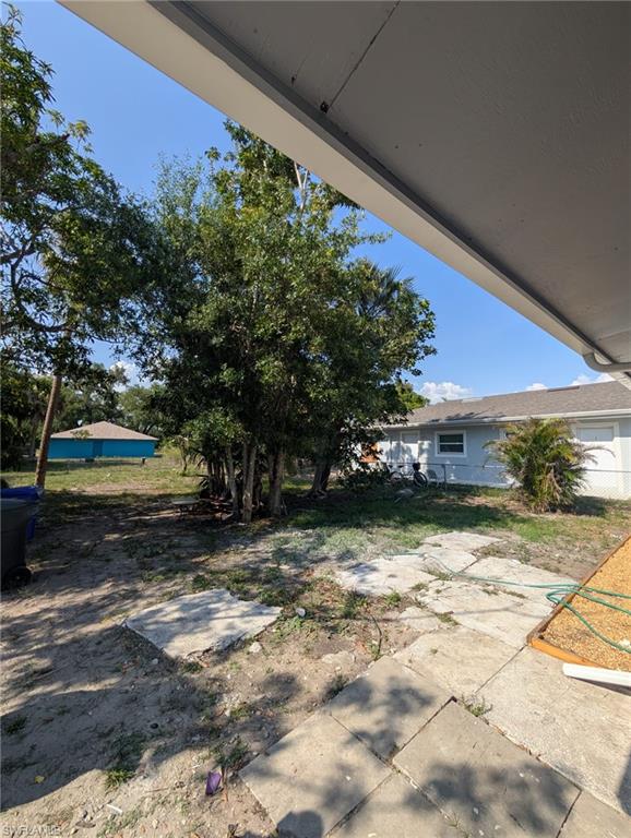 Expansive backyard featuring mature trees, partial concrete patio, and a visible portion of the property's exterior