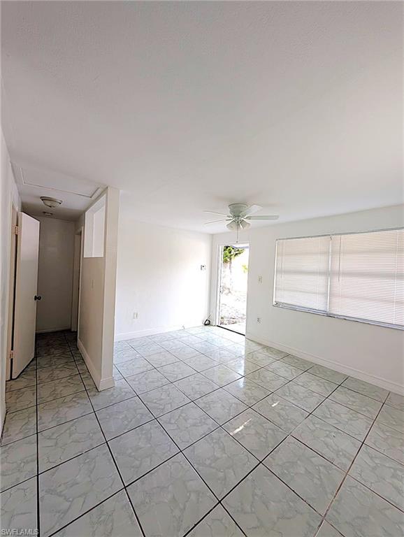 Spacious interior featuring large format tile flooring, a white ceiling fan, and white window blinds