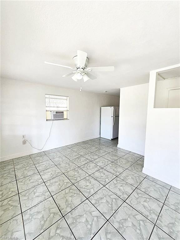 Spacious room featuring light-toned tile flooring, a ceiling fan with integrated lighting, and white painted walls
