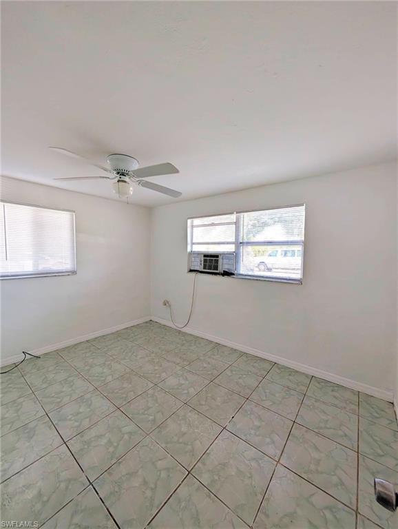 Room featuring light green floor tiles, white walls, two windows, and a ceiling fan with integrated lighting