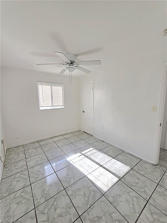 Room featuring light-toned square tile flooring, a window with horizontal blinds, a white ceiling fan, and white walls