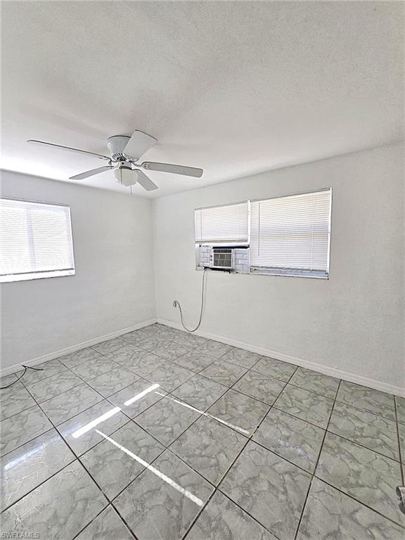 Room featuring light-toned tile flooring, white walls, and a ceiling fan with integrated lighting