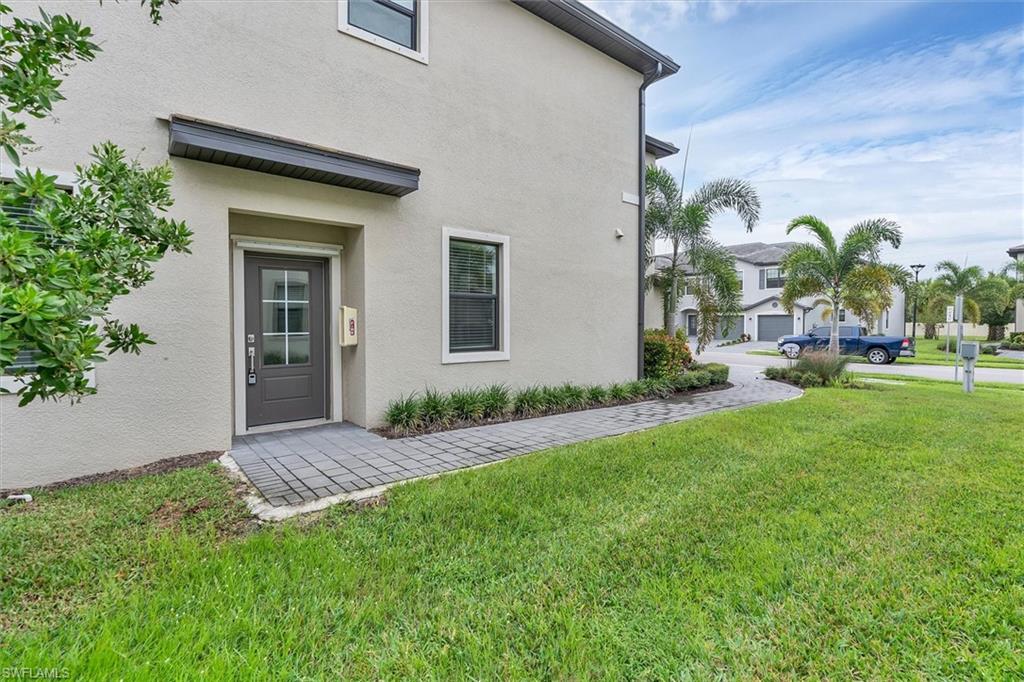 View of exterior entry with stucco siding and a yard