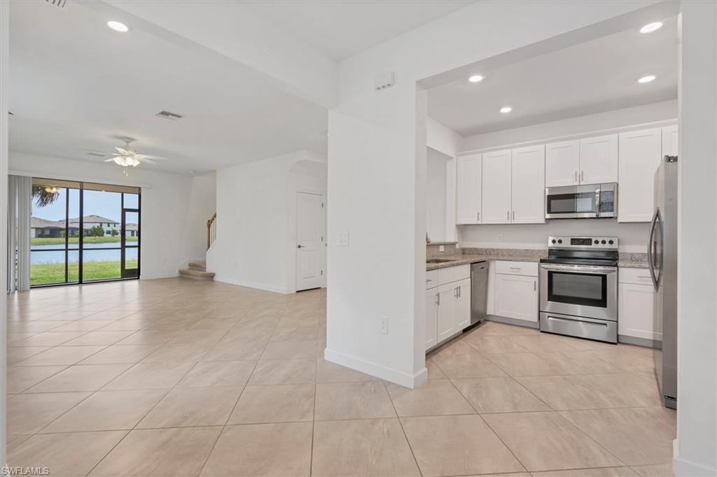 Kitchen featuring recessed lighting, stainless steel appliances, white cabinets, open floor plan, and light tile patterned floors