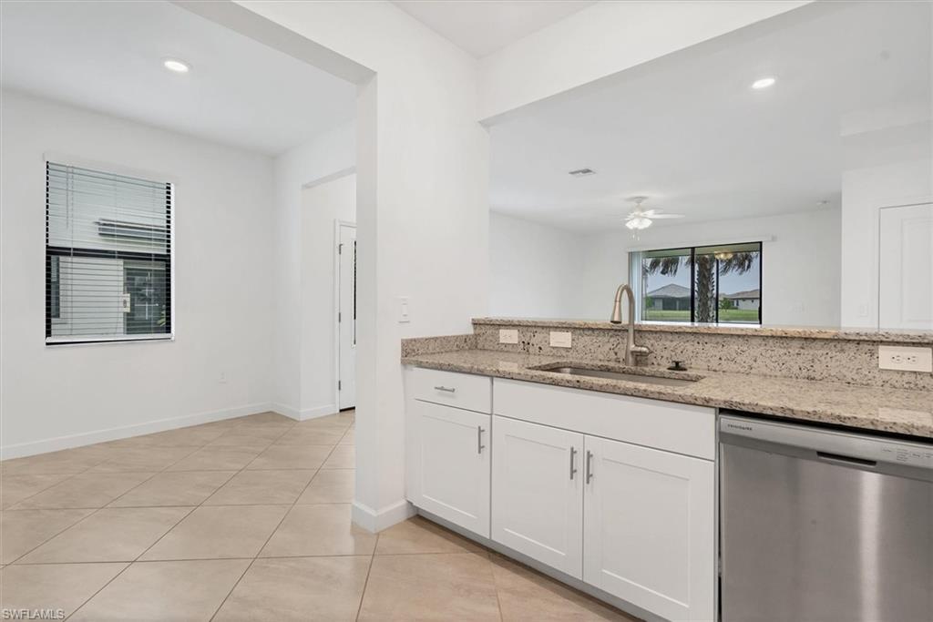 Kitchen featuring dishwasher, light stone countertops, white cabinetry, light tile patterned floors, and recessed lighting