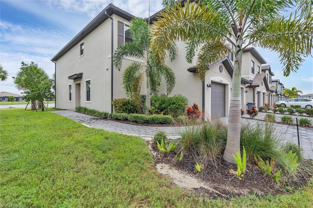View of side of property with stucco siding, a yard, a residential view, an attached garage, and driveway
