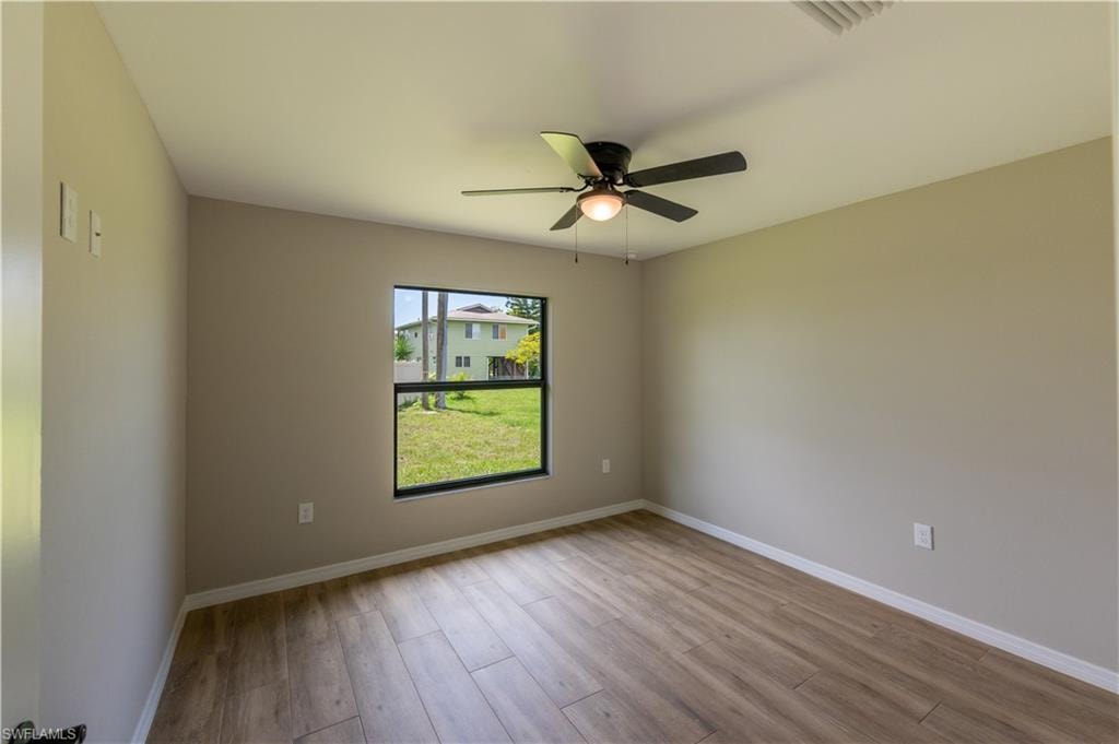 Neutral wall paint with wood-finish flooring, featuring a ceiling fan with integrated lighting