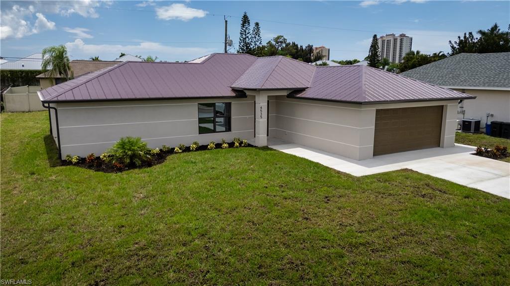 Exterior residence featuring a brown metal roof, light-colored stucco siding, a two-car garage with a wood-finish door, and a concrete driveway