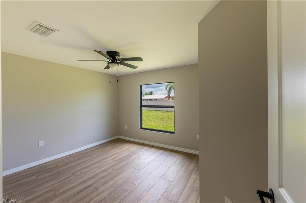 Wood-finish flooring, neutral wall tones, ceiling fan, and a window with exterior views