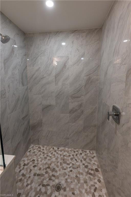 Walk-in shower featuring large format wall tiles and a pebble-style floor