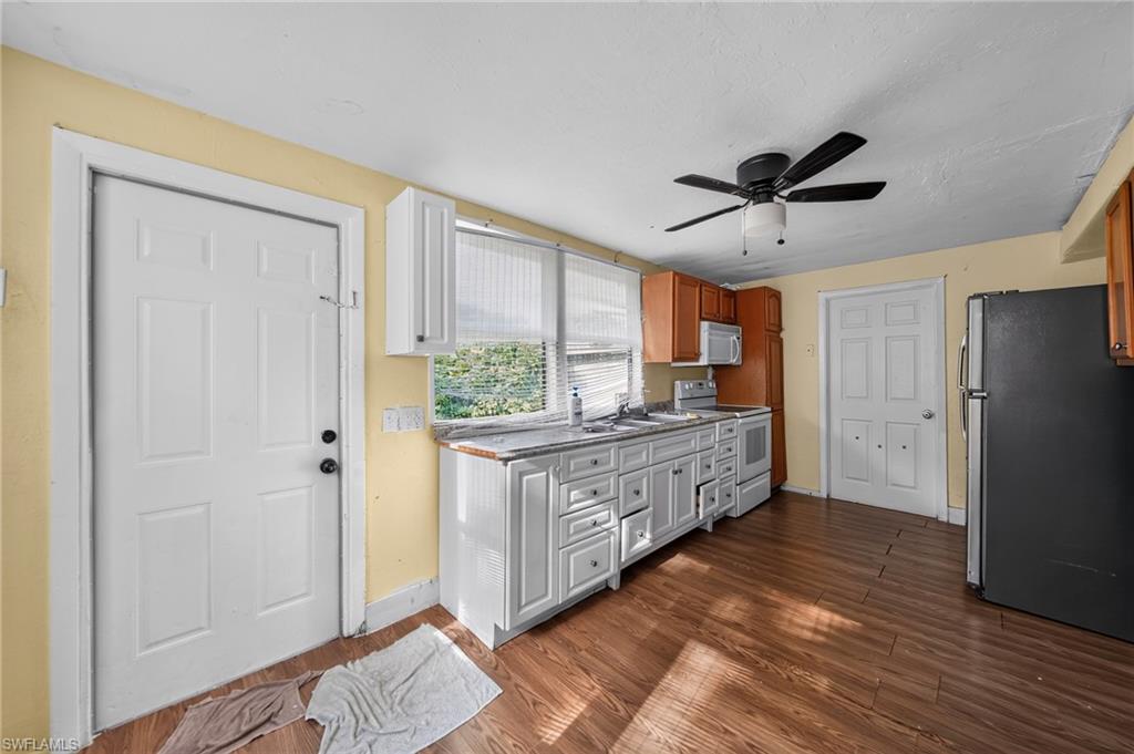 Kitchen featuring wood-finish flooring, white cabinetry, a built-in microwave, and a ceiling fan with integrated lighting