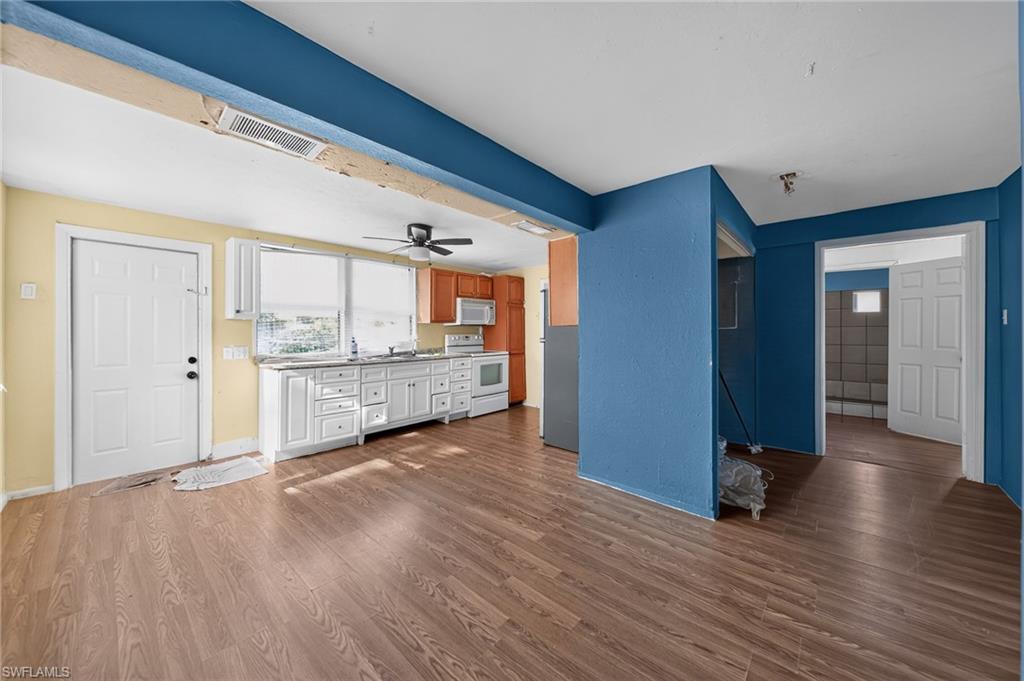 Spacious kitchen area featuring wood-finish flooring, white cabinetry, integrated appliances, and a ceiling fan