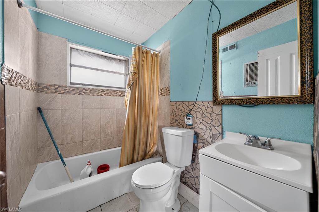Bathroom featuring a white bathtub, a single-pane window, a toilet, a vanity with an integrated sink, and a framed mirror