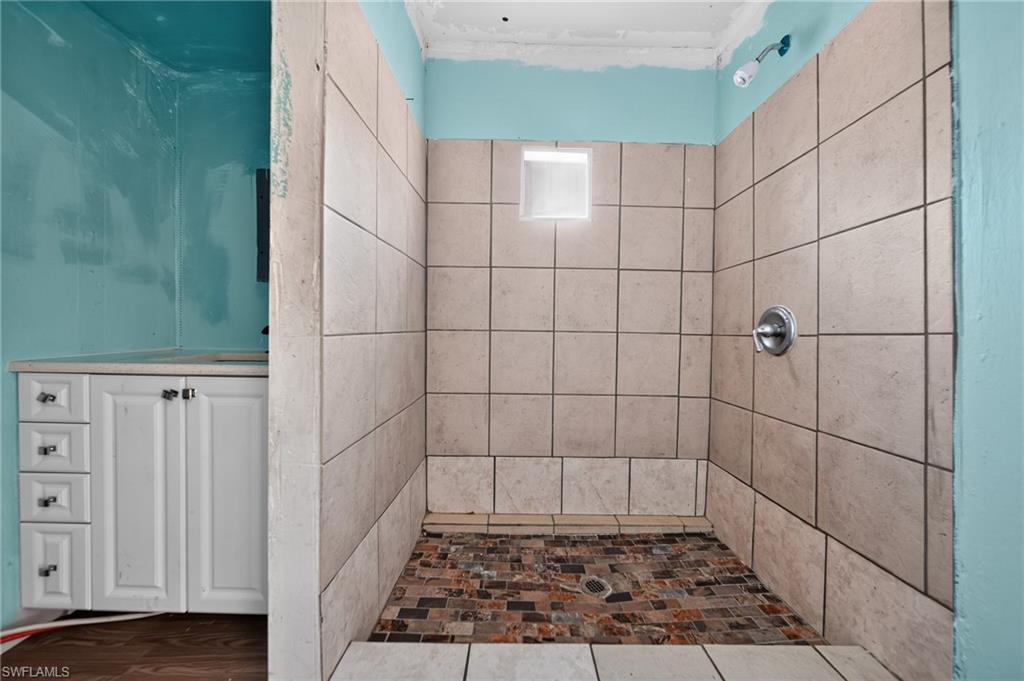 Tiled shower enclosure featuring a mosaic floor and a wall-mounted shower fixture