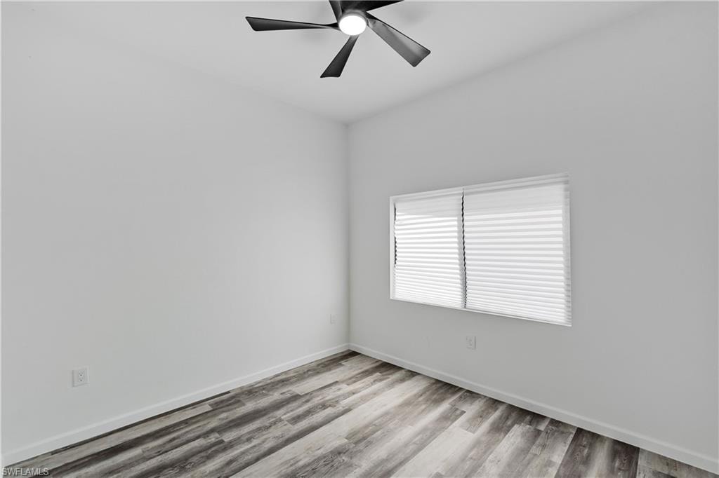 Interior room featuring wood-finish flooring, white walls, and a contemporary ceiling fan