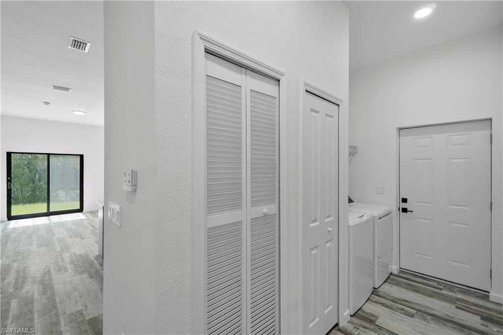 Utility area featuring wood-finish flooring, a louvered bi-fold closet, a six-panel door, and recessed lighting