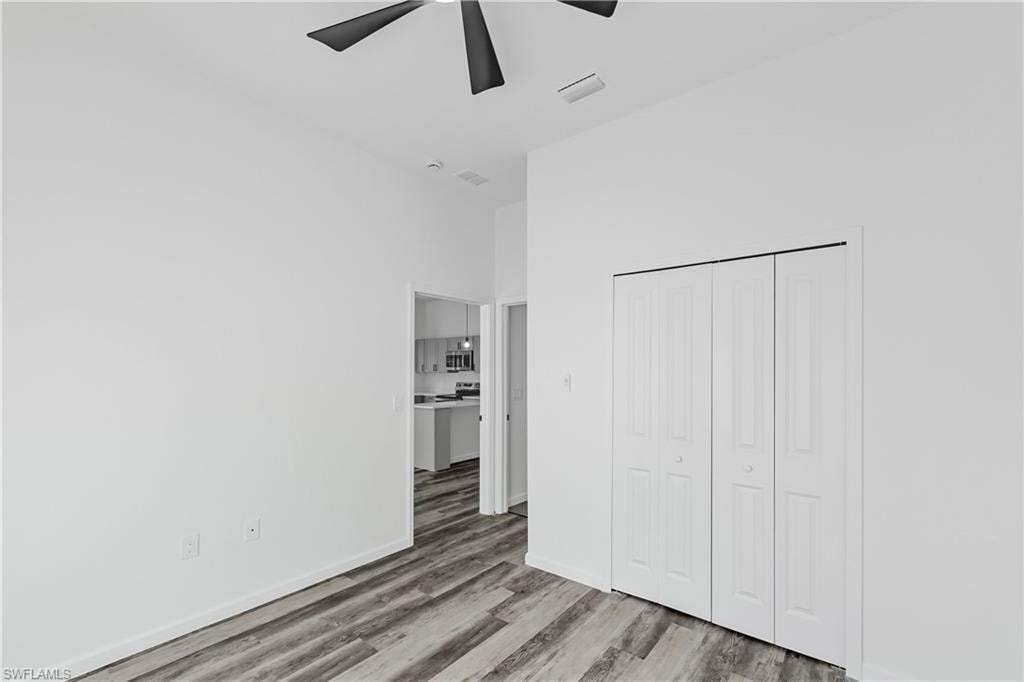 Spacious room featuring wood-finish flooring, a contemporary ceiling fan, and bi-fold closet doors