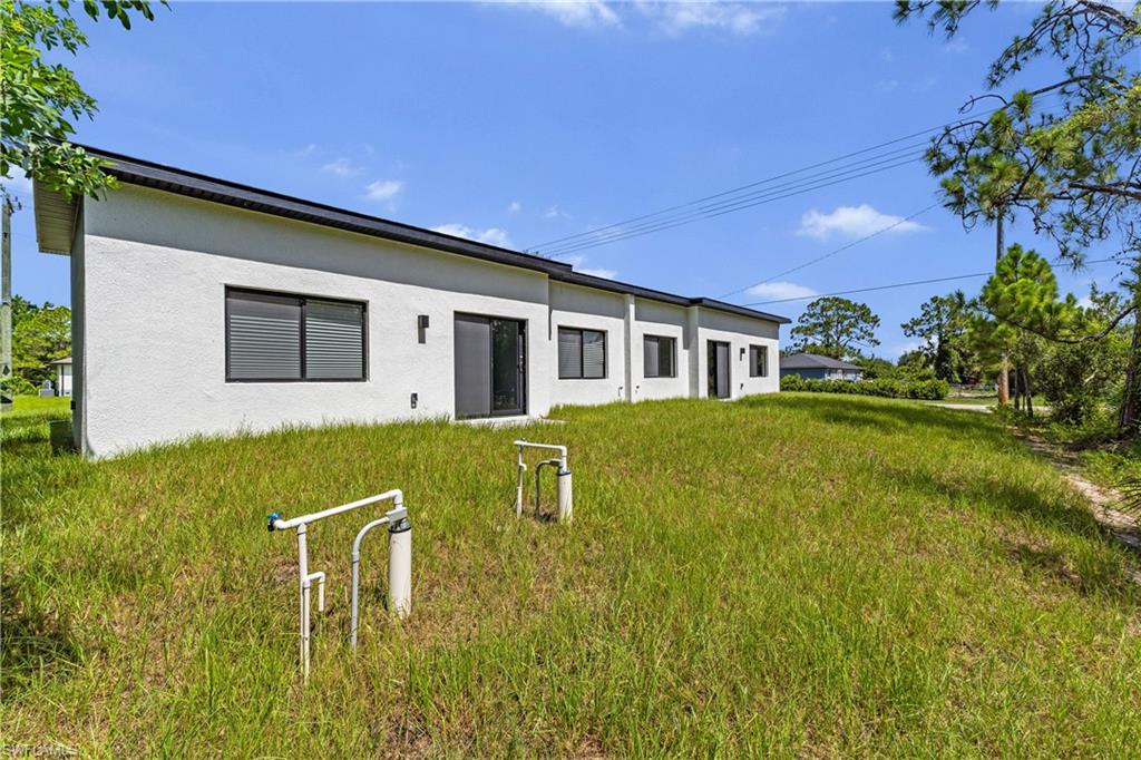 Contemporary stucco exterior with a black flat roofline, multiple windows with dark frames, and sliding glass doors