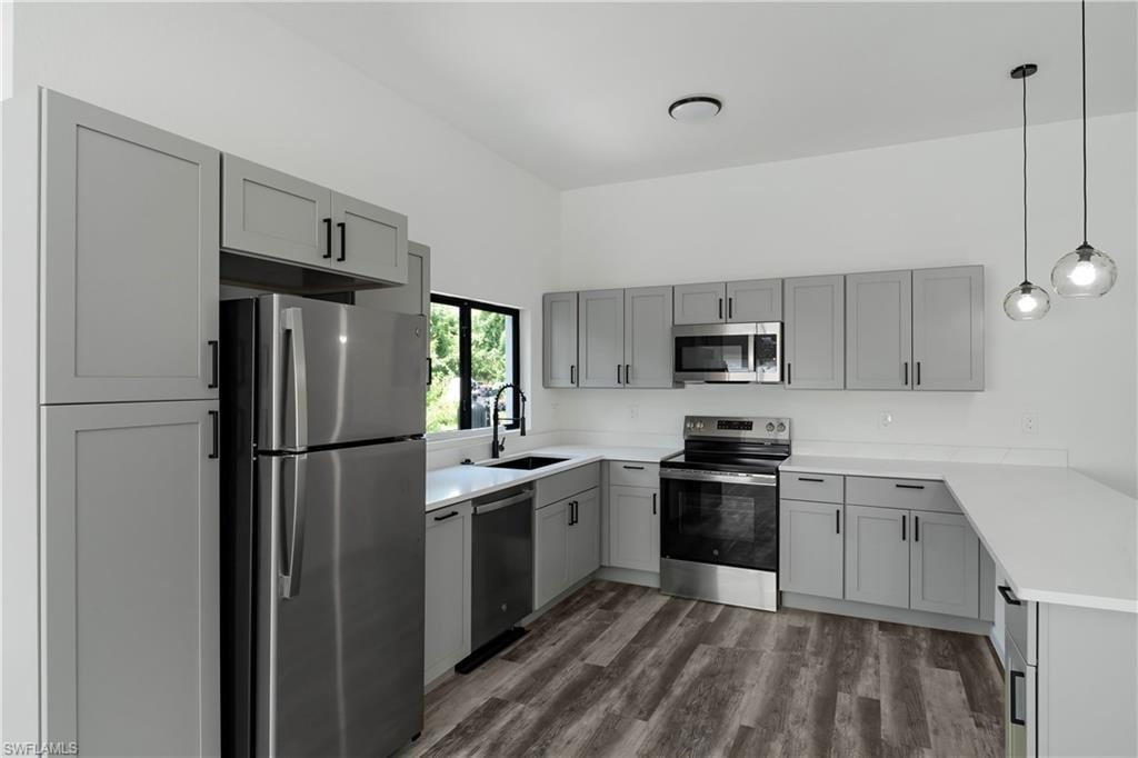 Contemporary kitchen featuring light gray shaker cabinetry with matte black hardware, white countertops, and wood-finish flooring